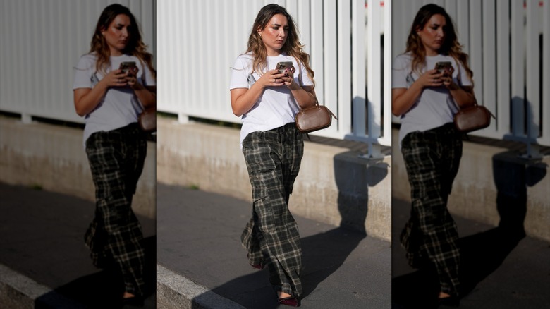 A woman wearing plaid trousers and a white tee