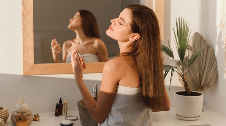 woman using perfume in a bathroom