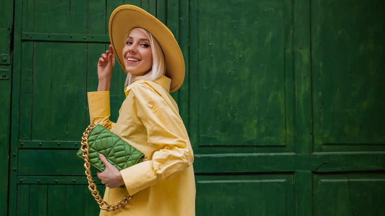 Woman in yellow holding green handbag