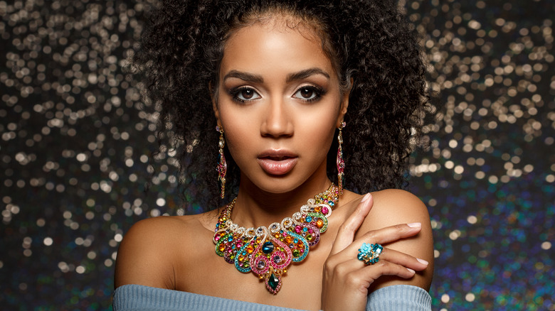 A woman wearing earrings, a necklace, and a ring