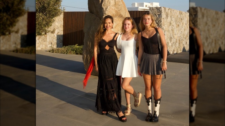 Jessica Alba posing outside in a black dress with her daughters Honor and Haven.