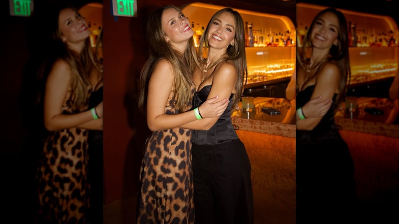 Jessica Alba hugging her daughter Honor and posing for a photo in a bar.