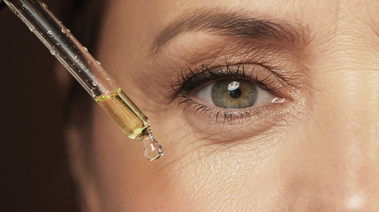 Woman applying serum to her face with a dropper