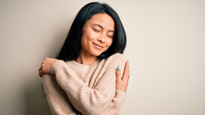 smiling single woman hugging herself