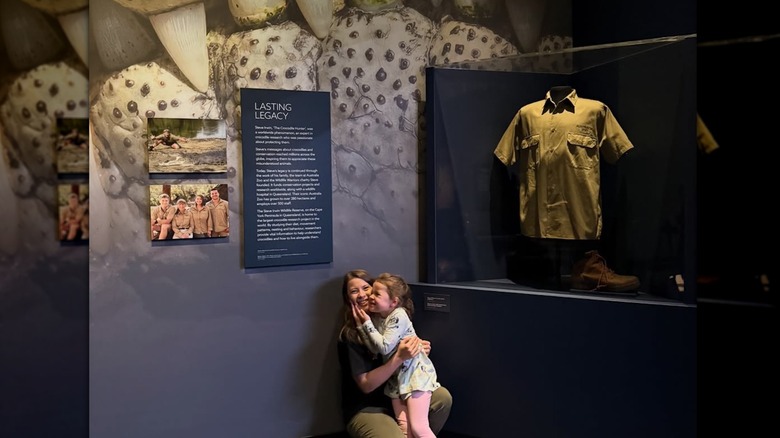 Bindi Irwin cuddling with her daughter Grace in front of Steve Irwin's shirt