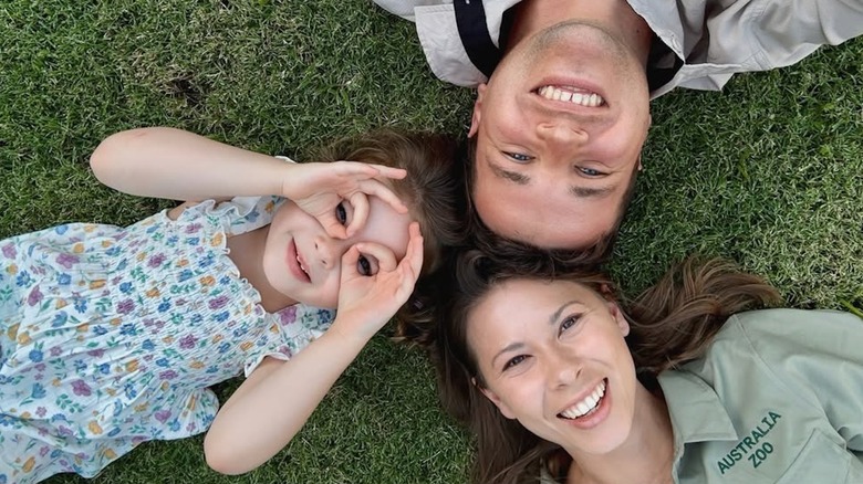 Bindi Irwin, Chandler Powell, and Grace lying in the grass