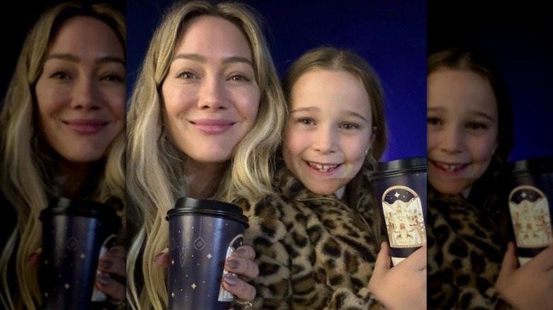 Hilary Duff wears her blond hair down in loose waves while posing with her daughter Banks while holding hot chocolates.