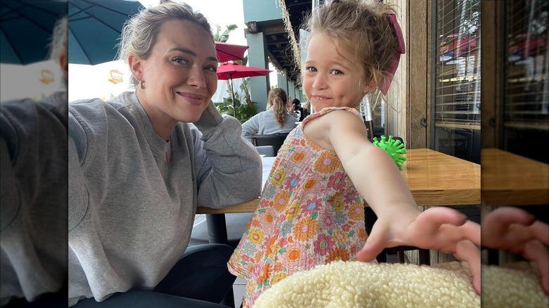 Hilary Duff wears her hair up in a messy bun and a gray sweatshirt while sitting with Banks at a sushi restaurant.