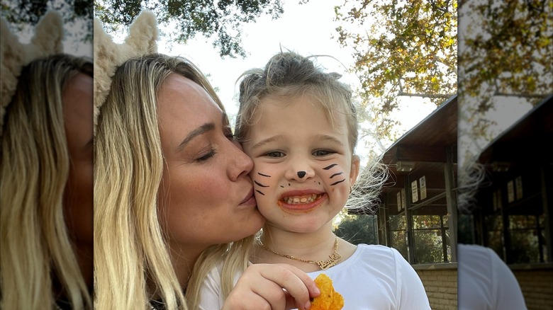 Hilary Duff wears cat ears with her blond hair down while kissing daughter Banks on the cheek celebrating Halloween.