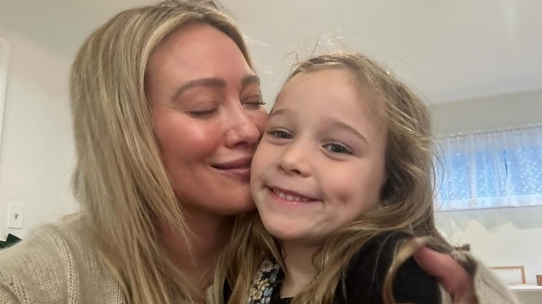 Hilary Duff wears her blond hair down and closes her eyes while embracing daughter Banks for a selfie in December 2023.