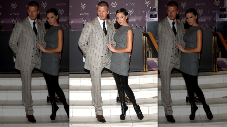 Victoria Beckham in a gray dress and boots with David Beckham