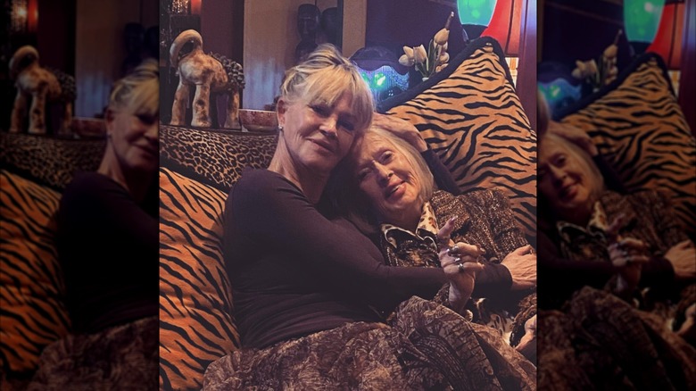 Melanie Griffith cuddles up to her mother Tippi Hedren while sitting on an animal print couch