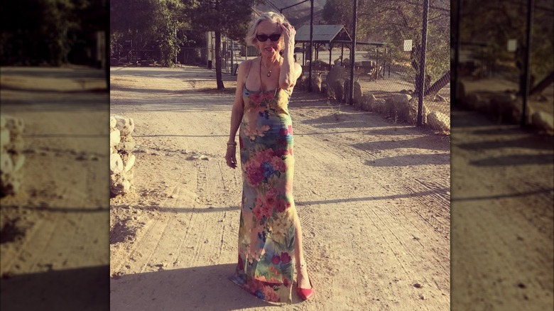 Tippi Hedren is photographed on a dirt road wearing a floral floor-length gown and red shoes