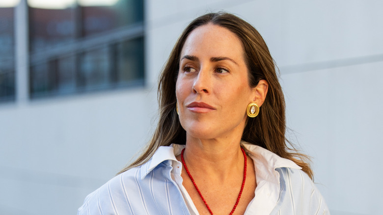 A woman wearing gold and crystal button earrings.