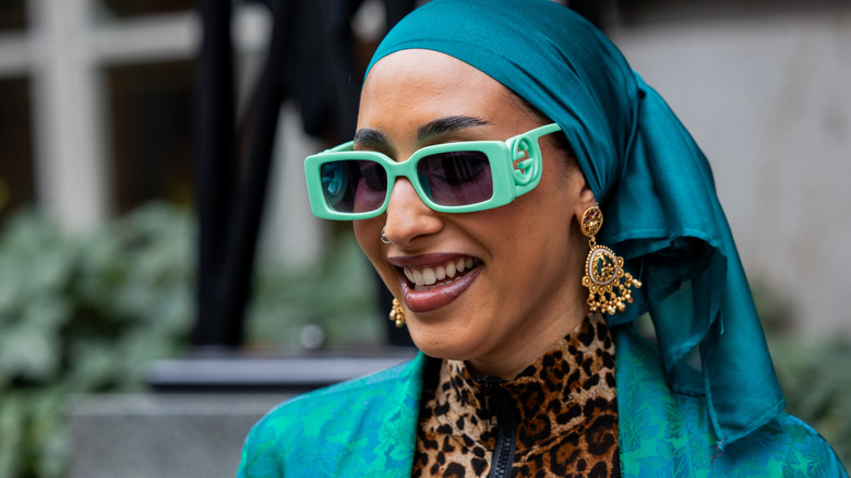 A woman wearing bulky chandelier earrings.