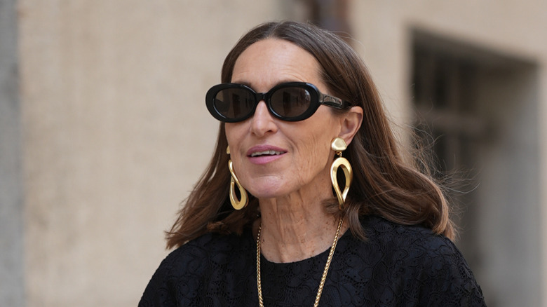 A woman wearing a pair of gold door knocker earrings.