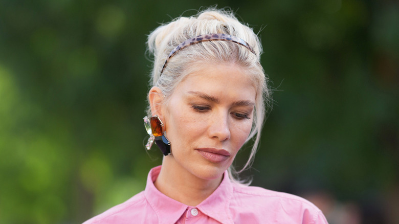 A woman wearing a statement gemstone earring.