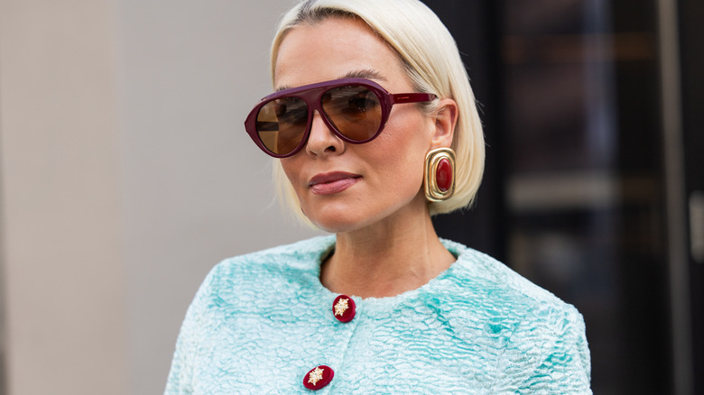 A woman wearing rectangular earrings with red gemstones.