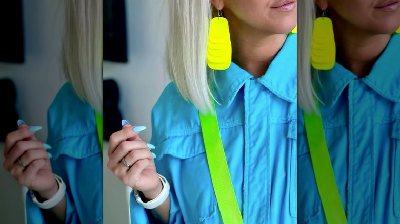 A woman wearing neon yellow chandelier earrings