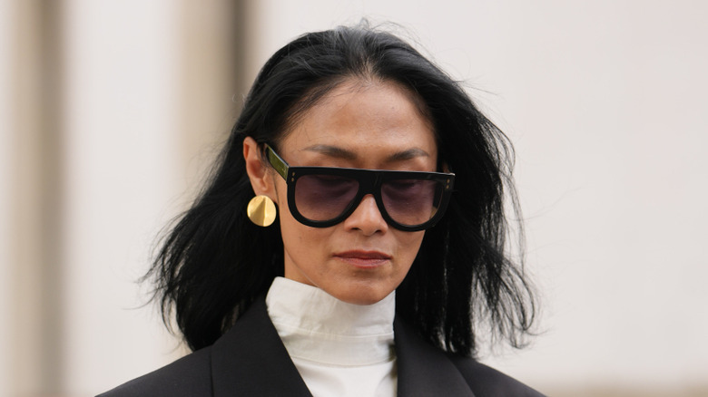 A woman wearing gold disc earrings.