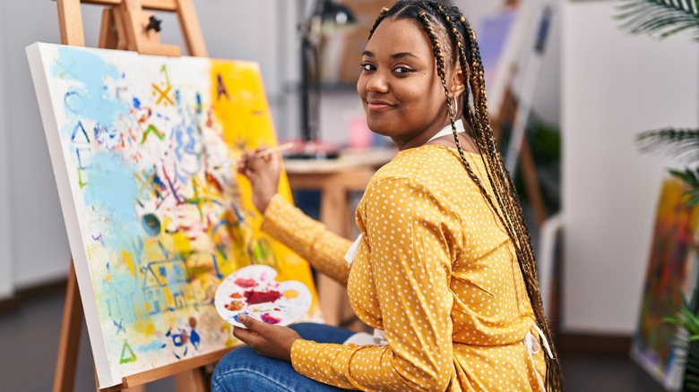 woman painting on canvas in studio