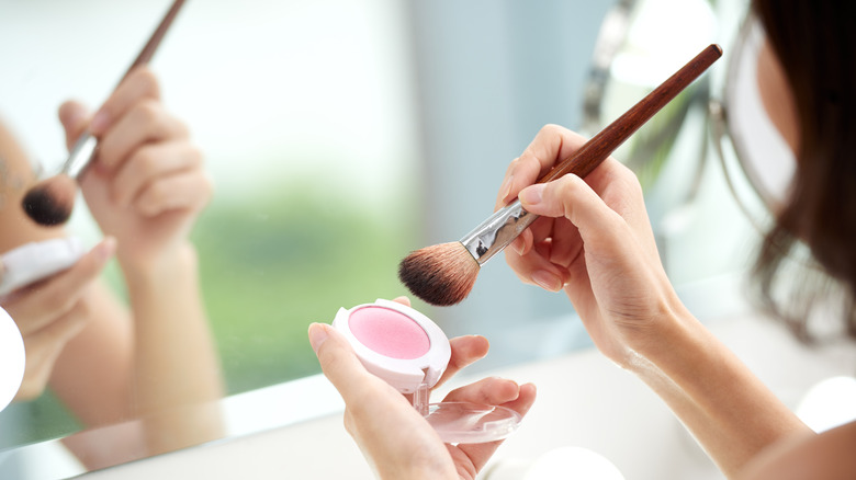 Woman applying blush with brush