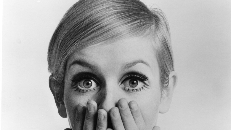 Twiggy hands covering mouth