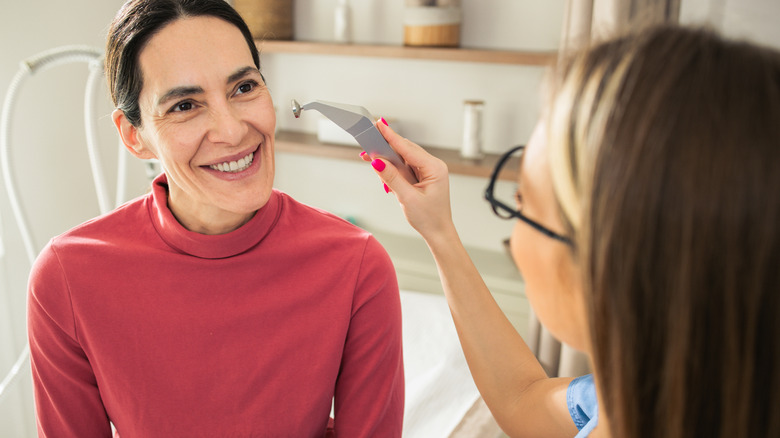 woman smiles as she receives cosmetic service