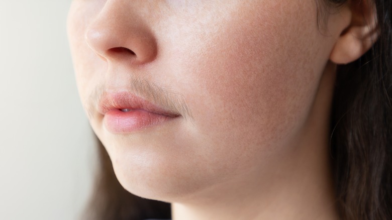 Female presenting face with a mustache