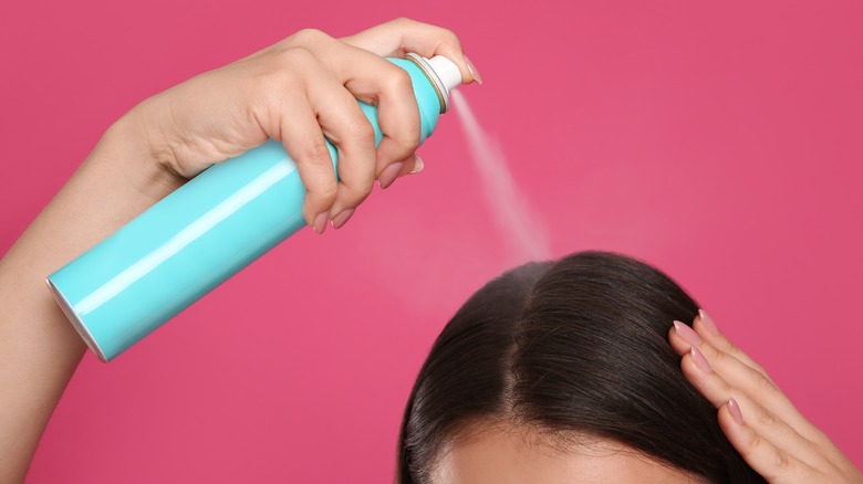 Woman spraying dry shampoo onto hairline