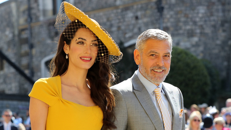 George and Amal clooney in a yelllow dress at the royal wedding of Prince Harry and Meghan Markle