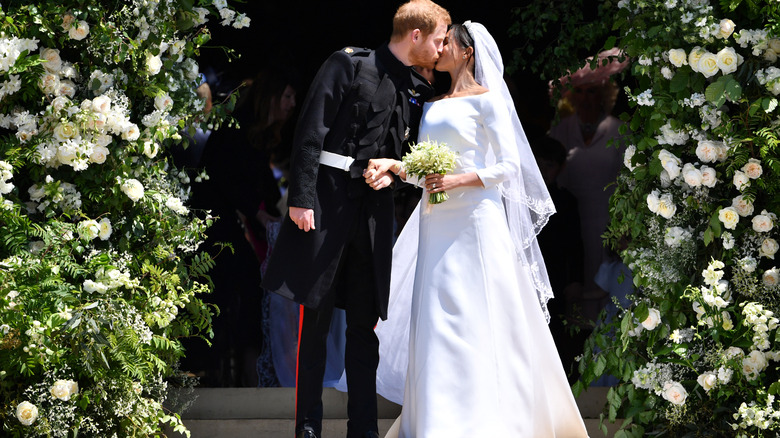 Meghan Markle in her wedding dress and Prince Harry sharing a kiss on their wedding day