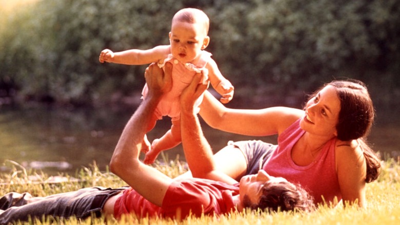 A couple playing with their baby outside in the 1970s