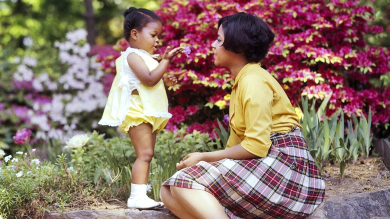 A baby showing her mother a flower in the 1970s