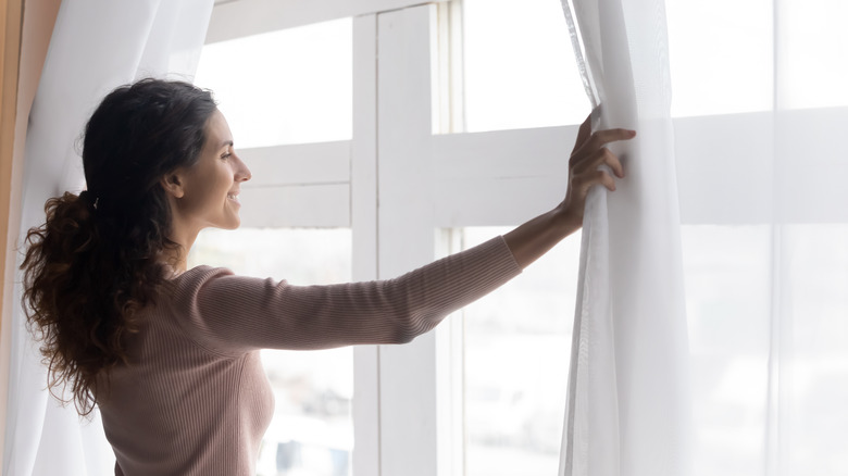 woman smiling opening curtains