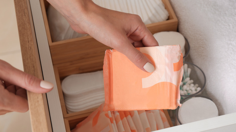 Person taking menstrual pad from drawer