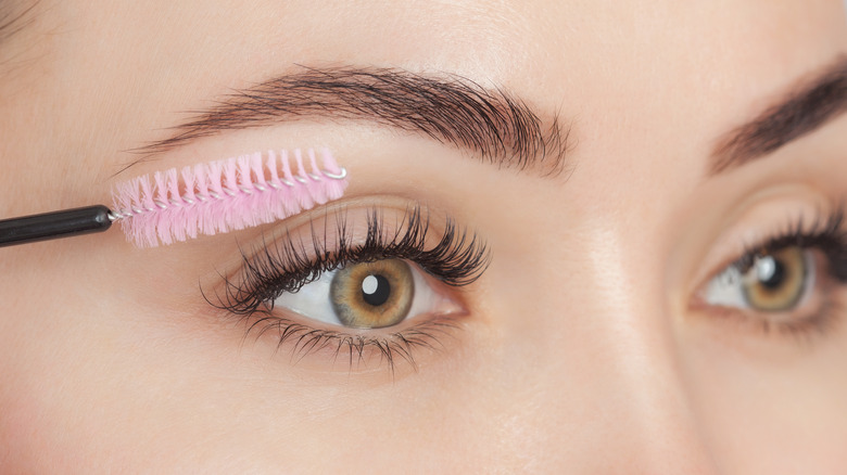 A woman brushing her eyelashes