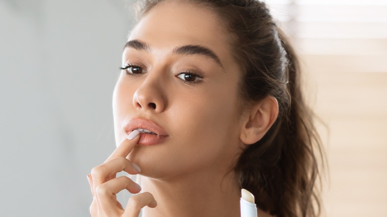 Woman applying lip balm with fingers 