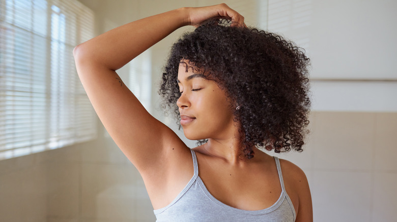 young woman smelling underarms 