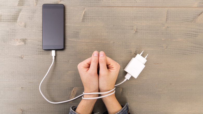 Phone charger cord as handcuffs around wrists 