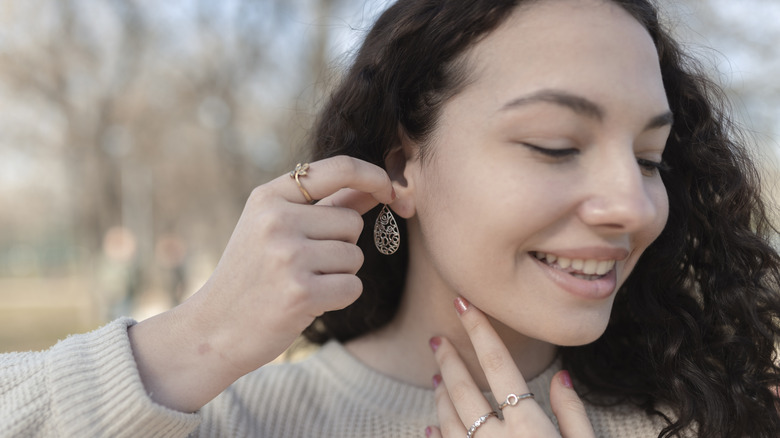 Close-up of hands inserting new jewelry into a fully healed ear piercing.