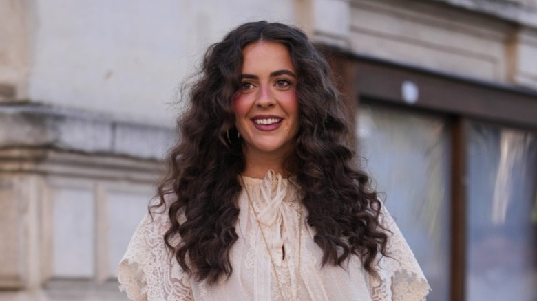 A woman with long, voluminous curly hair smiles