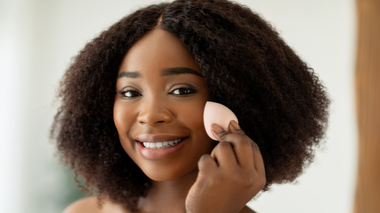 Black woman applying foundation 