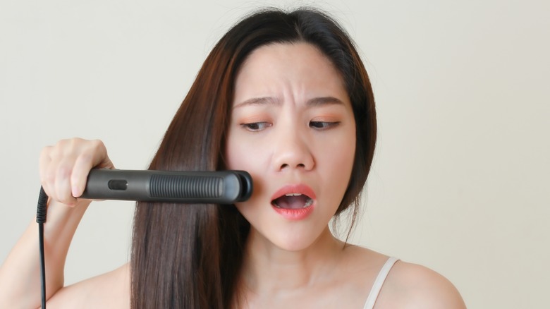 Concerned woman using flat iron