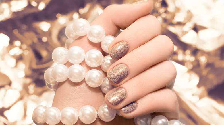hand with glitter gold nail polish