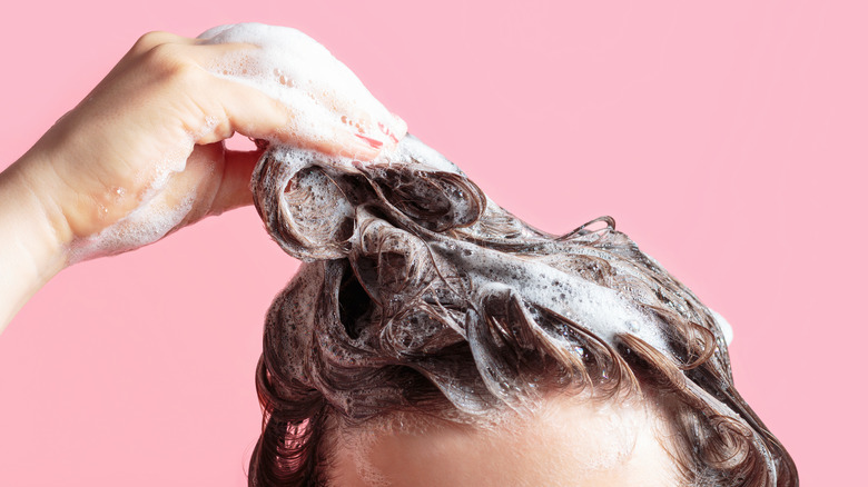 Person washing hair pink background