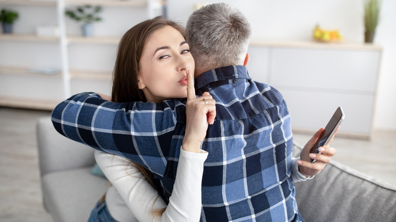 Women hugging man saying shh