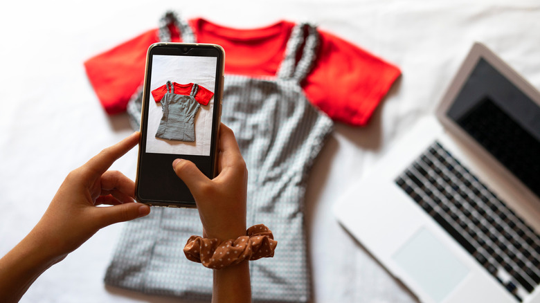 woman taking picture of clothes on bed