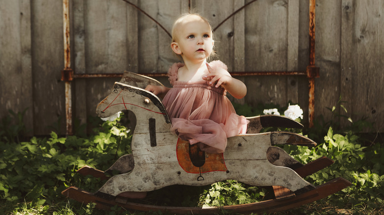 A baby girl on a vintage rocking horse