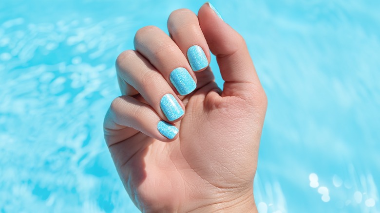 blue manicure in front of water